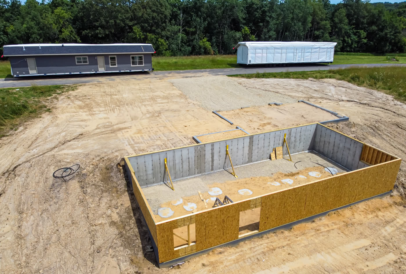 Modular home sections beside a new foundation (watch: NAR on frameless manufactured homes)